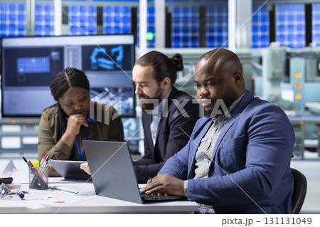 Investor in industrial plant using laptop to review manufacturing expansion documents. African american businessman looking at data on notebook to evaluate investment strategy 131131049