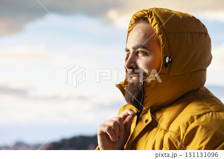 Determined climber standing at the summit enjoys peaceful moment of success. Vast sky, mountain range and fresh air highlighting the essence of freedom, wellness and exploration. 131131096