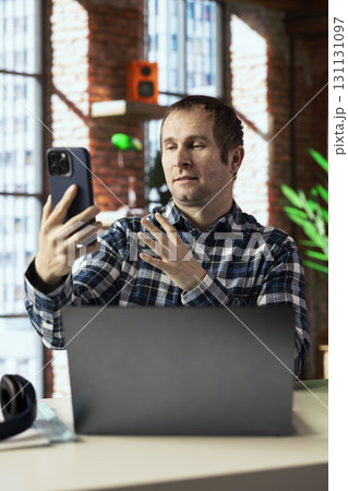 Manager calls employee remotely using internet videocall on smartphone to offer negative feedback on project progress. Angry team leader berating teleworker at home in teleconference meeting 131131097