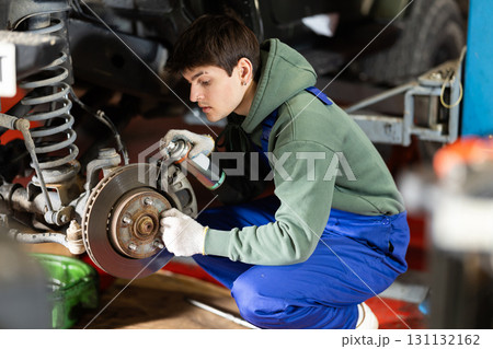 Mechanic applying anti-rust liquid to bolts on car wheel hub Mechanic applying anti-rust liquid to bolts on car wheel hub 131132162