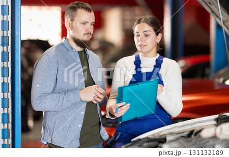 Female worker of auto service speaking to male client concerning notes wrote down on paper Female worker of auto service speaking to male client concerning notes wrote down on paper 131132189