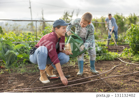 Woman and son planting seeds on farm Woman and son planting seeds on farm 131132402