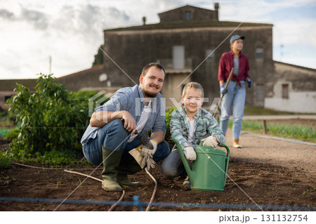 Young man with boy planting seeds in field Young man with boy planting seeds in field 131132754