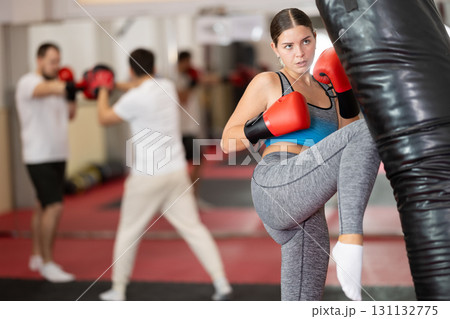 Girl punches and kicks punching bag in gym. Girl punches and kicks punching bag in gym. 131132775