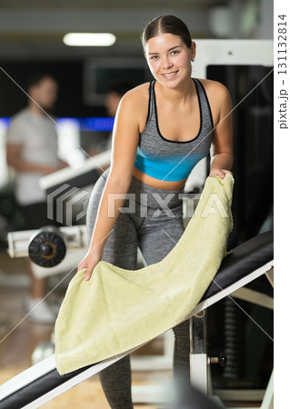 Girl puts towel on simulator and prepares equipment for training. Girl puts towel on simulator and prepares equipment for training. 131132814