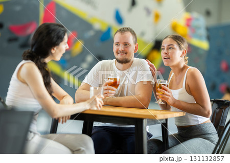 Man and two women talk at table on climbing wall Man and two women talk at table on climbing wall 131132857