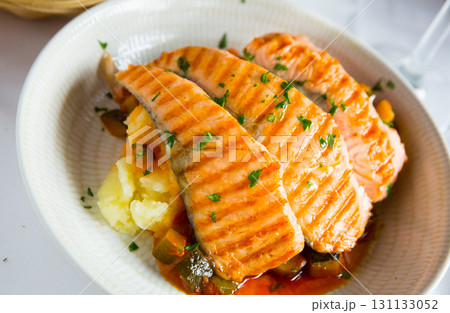 Tasty steak of grilled salmon in sauce with pepper and lemon on plate 131133052