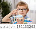 Young Boy with Glasses Holding a Toy Bell Indoors 131133292