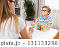 Child Engaged in Educational Activity with Teacher at Table 131133296
