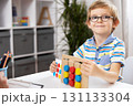 Smiling Child Engaged in Educational Activity with Colorful Shapes 131133304