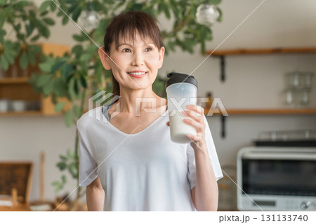 家・自宅のリビングでトレーニング後にプロテイン・EAAを飲むアジア人女性 131133740