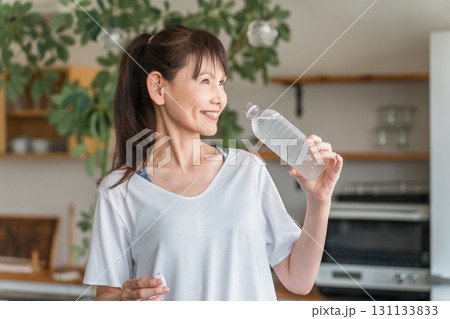 自宅トレーニング後にペットボトルのミネラルウォーターで水分補給をするアジア人女性 131133833