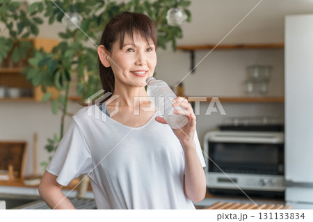 自宅トレーニング後にペットボトルのミネラルウォーターで水分補給をするアジア人女性 自宅トレーニング後にペットボトルのミネラルウォーターで水分補給をするアジア人女性 131133834