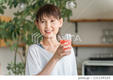 キッチンの前でトマトジュース,アセロラ,BCAA,赤いドリンクを飲む若いアジア人女性 131134320