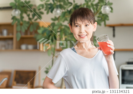 キッチンの前でトマトジュース,アセロラ,BCAA,赤いドリンクを飲む若いアジア人女性 キッチンの前でトマトジュース,アセロラ,BCAA,赤いドリンクを飲む若いアジア人女性 131134321