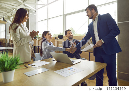 Business people shaking hands celebrating success or making a deal in office. 131134369