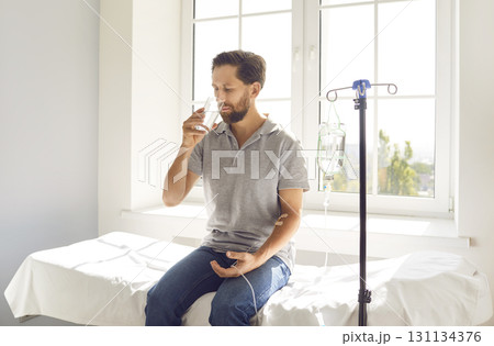 Man sitting at doctor's office in clinic while receiving IV drip infusion and vitamin therapy Man sitting at doctor's office in clinic while receiving IV drip infusion and vitamin therapy 131134376