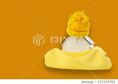 A small house model is dressed warmly in yellow knitwear and hat A small house model is dressed warmly in yellow knitwear and hat 131134702