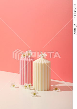 Two colorful candles sit on a pastel surface adorned with small flowers 131134704