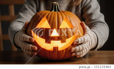 Child's Mummy Hands Holding Friendly Smiling Jack-o-Lantern Pumpkin 131135463