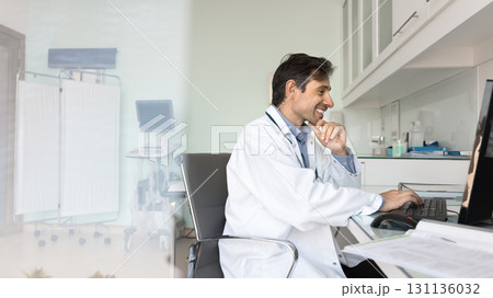 Happy mature male doctor using pc at workplace watching webinar 131136032