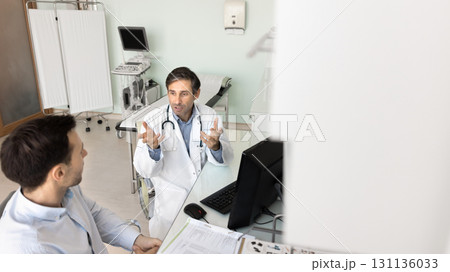 Male doctor discuss treatment plan with patient in examination room 131136033