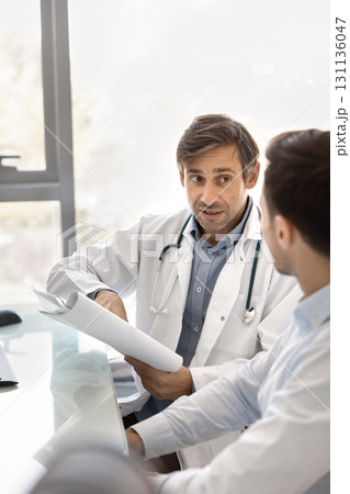 Doctor and pharma representative discuss documents at clinic office desk 131136047