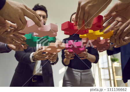 Team of business people joining parts of a jigsaw puzzle to illustrate the teamwork concept 131136662