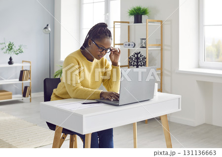 Young woman sitting at her desk at home and working on her modern laptop computer 131136663