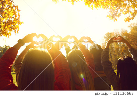 Group of young people doing heart shape gestures in beautiful autumn park at sunrise 131136665