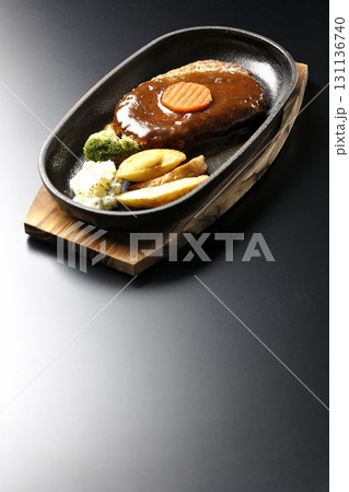 付け合わせでポテトフライ、ポテトサラダ、ブロッコリーが乗ってるハンバーグプレートを黒背景で撮影 付け合わせでポテトフライ、ポテトサラダ、ブロッコリーが乗ってるハンバーグプレートを黒背景で撮影 131136740