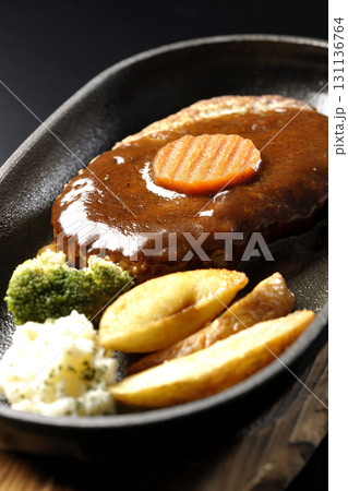 付け合わせでポテトフライ、ポテトサラダ、ブロッコリーが乗ってるハンバーグプレートを黒背景で撮影 付け合わせでポテトフライ、ポテトサラダ、ブロッコリーが乗ってるハンバーグプレートを黒背景で撮影 131136764