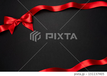 Festive red bow on black background with copy space, useful for holiday banners and online shop announcements Festive red bow on black background with copy space, useful for holiday banners and online shop announcements 131137405