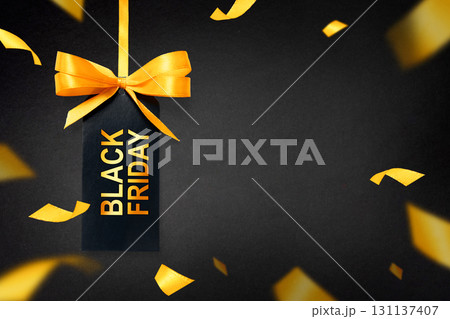Black Friday tag with golden ribbon on dramatic dark background with glowing confetti. Perfect for luxury sale campaigns and online promotions Black Friday tag with golden ribbon on dramatic dark background with glowing confetti. Perfect for luxury sale campaigns and online promotions 131137407