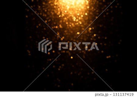 Glowing golden oval bokeh with shimmering light on dark background. Abstract festive glow with shimmering backlight for Christmas and holiday designs. 131137419