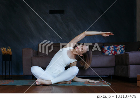 woman doing yoga at home stretching an arm 131137479