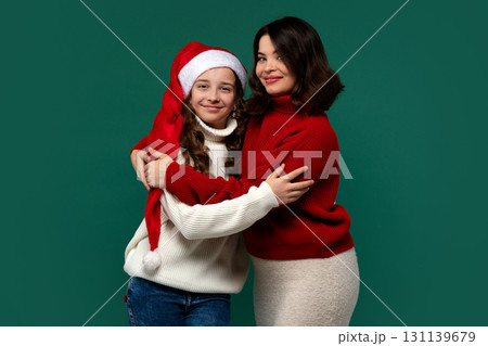 Mum and teenage daughter hug in festive sweaters, smiling warmly Mum and teenage daughter hug in festive sweaters, smiling warmly 131139679