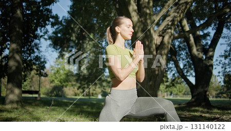 young beautiful white girl doing yoga in park among trees in clearing on summer day 131140122
