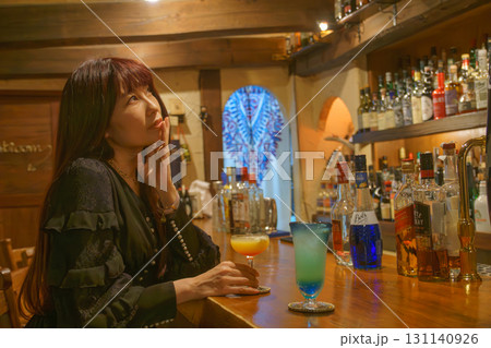 オーセンティックバーで一人お酒を味わう女性 131140926