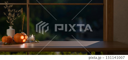 Glowing jack-o-lantern halloween pumpkins and candles on wooden table aside window in a dim lit room Glowing jack-o-lantern halloween pumpkins and candles on wooden table aside window in a dim lit room 131141007