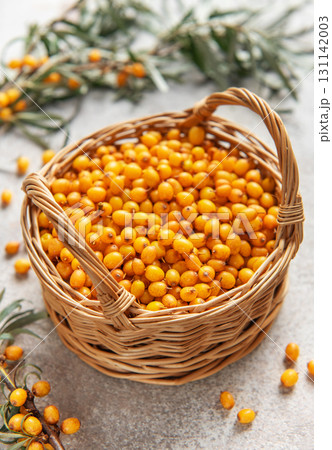 Fresh sea buckthorn berries overflowing a small wicker basket 131142003