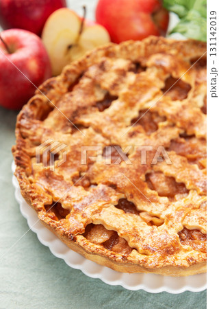 Freshly baked apple pie with red apples and leaves on green tablecloth 131142019