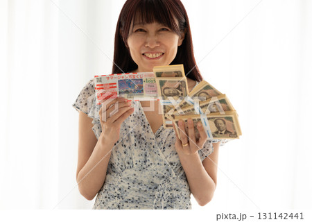 宝くじ高額当選して新札札束（渋沢栄一）を握る女性 131142441