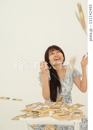 札束上に万札が降ってきて喜ぶ女性 札束上に万札が降ってきて喜ぶ女性 131142493