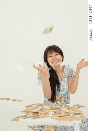 札束上に万札が降ってきて喜ぶ女性 札束上に万札が降ってきて喜ぶ女性 131142494