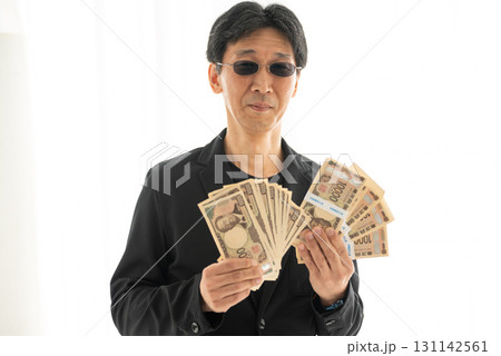 新札の一万円札札束を握る黒ずくめの男 131142561