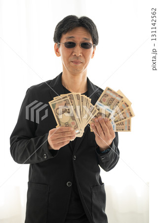 新札の一万円札札束を握る黒ずくめの男 131142562