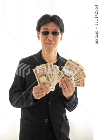 新札の一万円札札束を握る黒ずくめの男 131142563