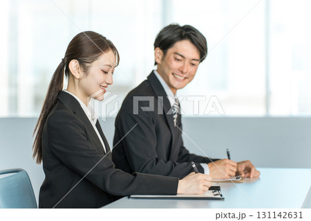 デスクに座り書類に記入するスーツ姿のビジネスマンとビジネスウーマン 131142631