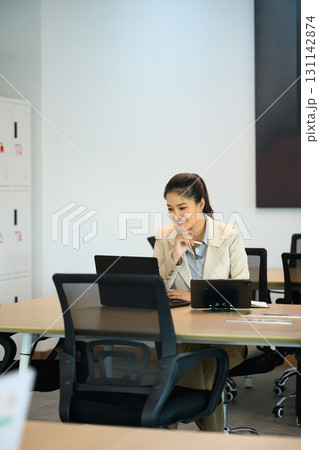Businesswoman working at desk with laptop in modern office, focused on professional tasks 131142874